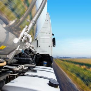 Cropped, motion-blurred close-up of semi on the road. No people are viewable in the shot. Square framed shot.